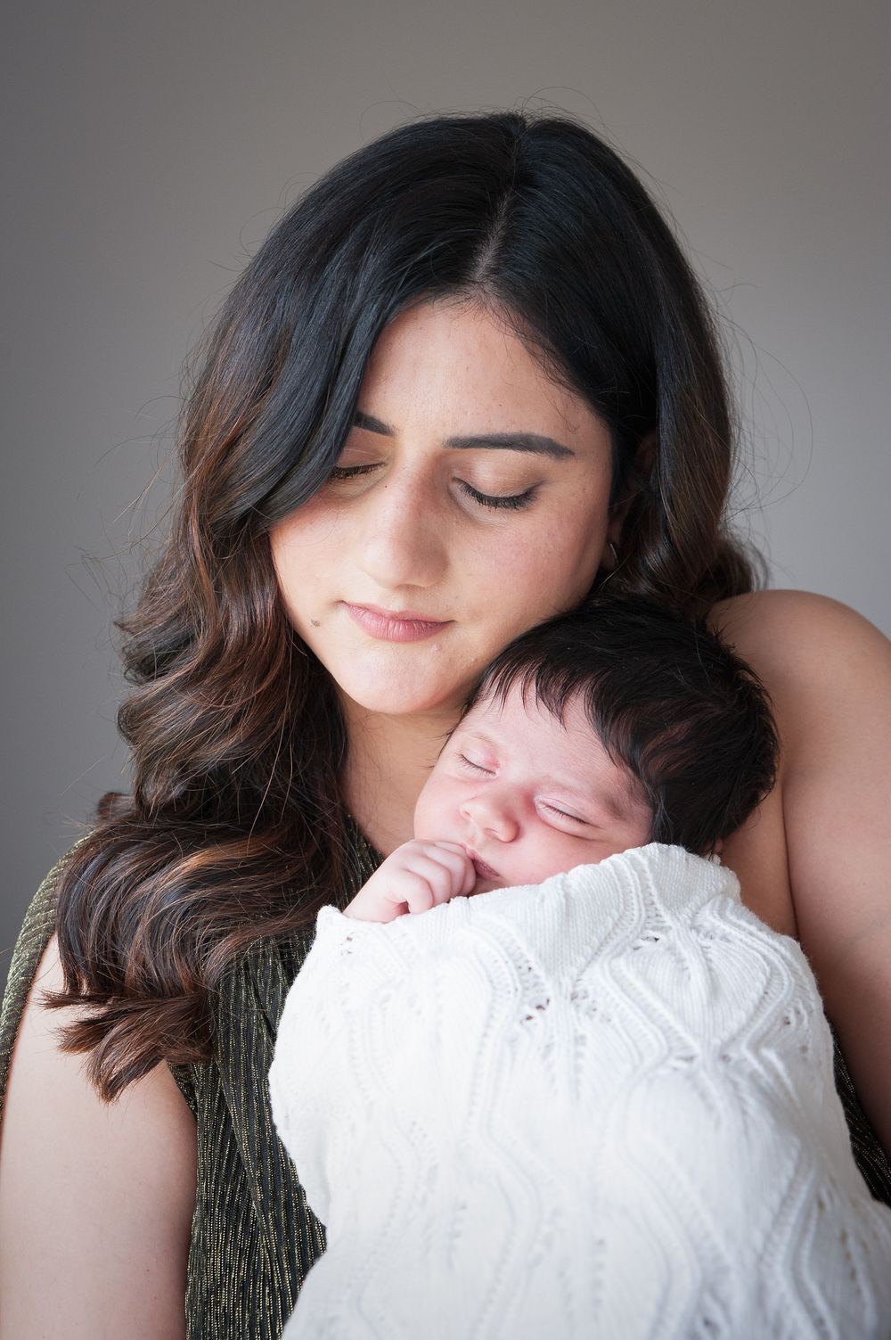 Someone wearing a knit sweater cuddles and kisses a white pillow while lounging in soft lighting.
Altona Family Photographer Melbourne