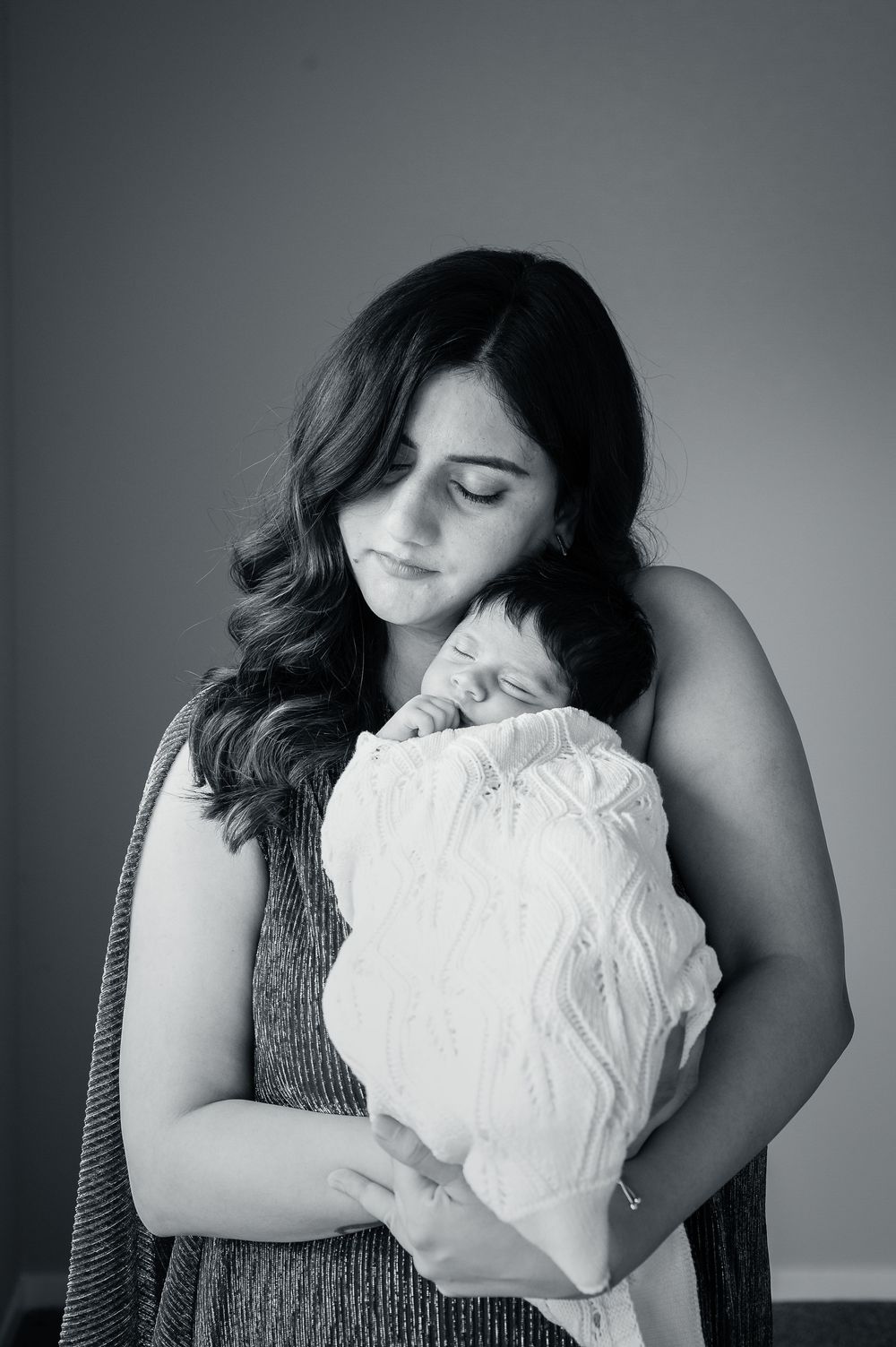 A tender black and white portrait of a mother holding and embracing her sleeping newborn baby.
Altona Family Photographer Melbourne