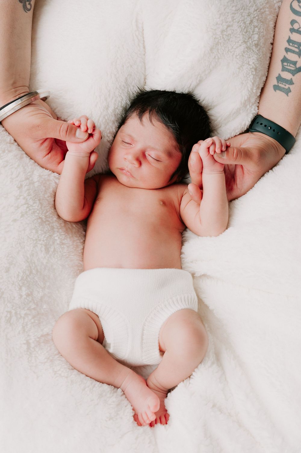 Sleeping newborn baby lying on soft white blanket with vulnerable expression and curled limbs.
Altona Family Photographer Melbourne