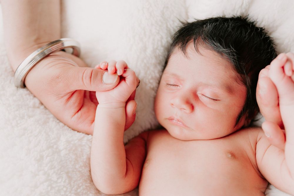 Peaceful sleeping newborn baby lying on white blanket with tiny hands raised.
Altona Family Photographer Melbourne