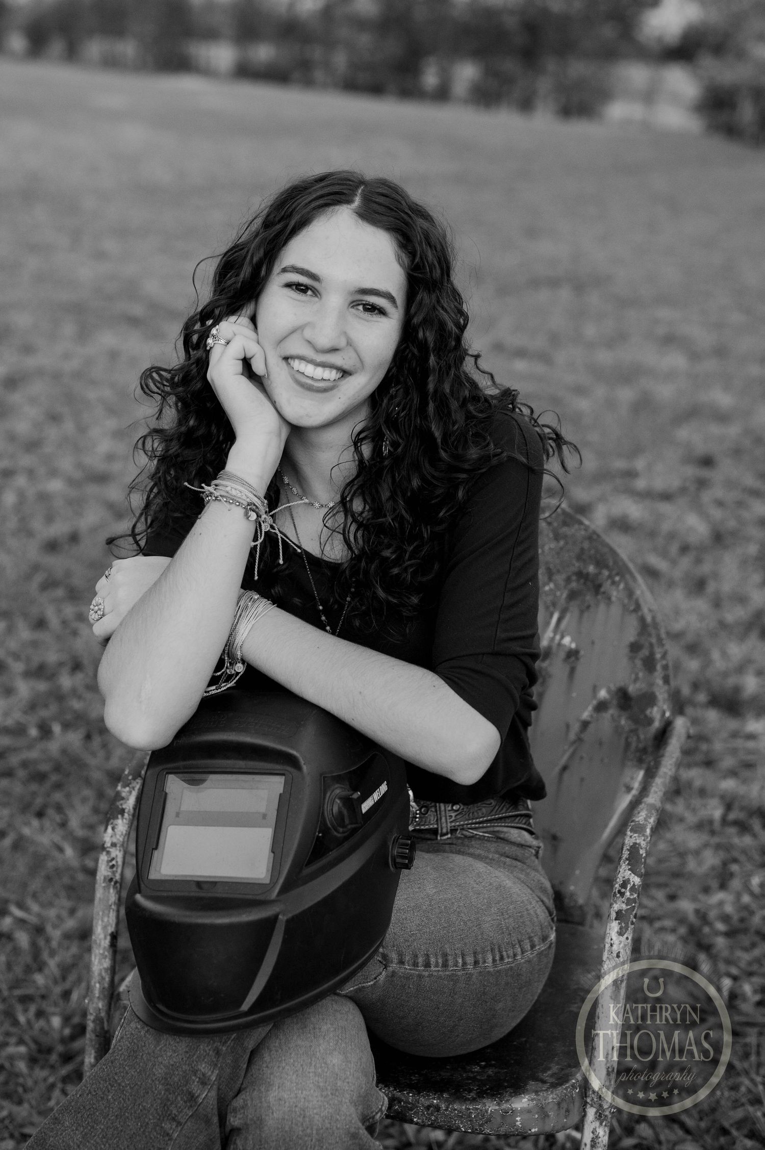 Black and white close-up portrait with welding helmet and natural outdoor setting.
