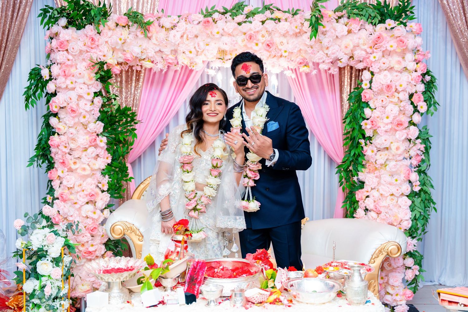 Celebratory toast under beautiful pink flower arch at wedding reception.
