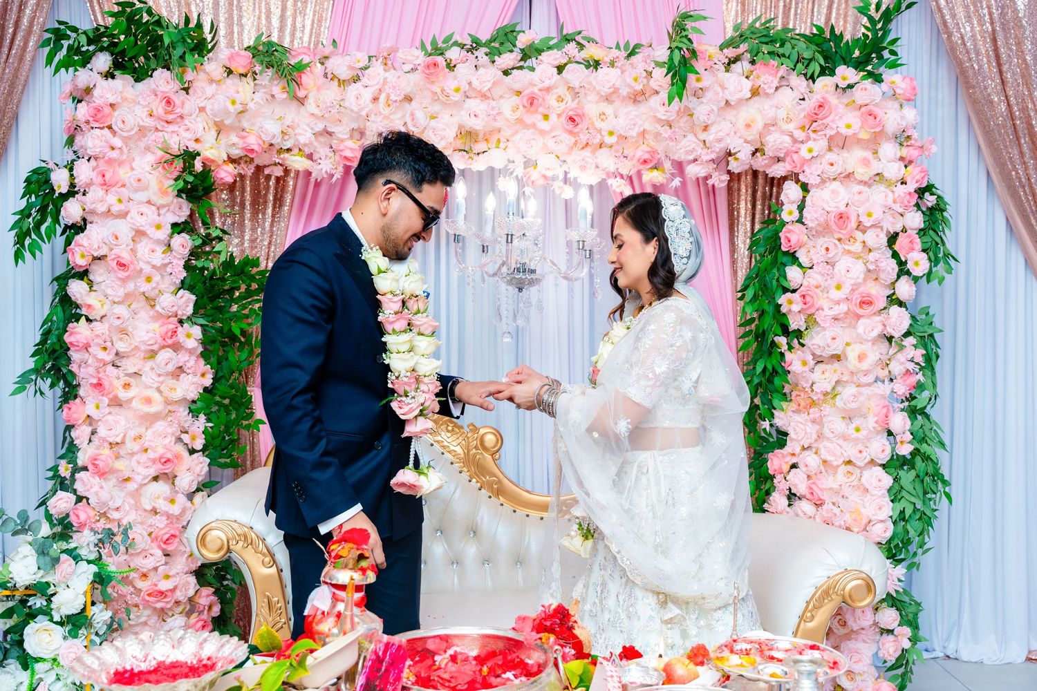 Wedding celebration featuring gift exchange under luxurious pink floral archway.