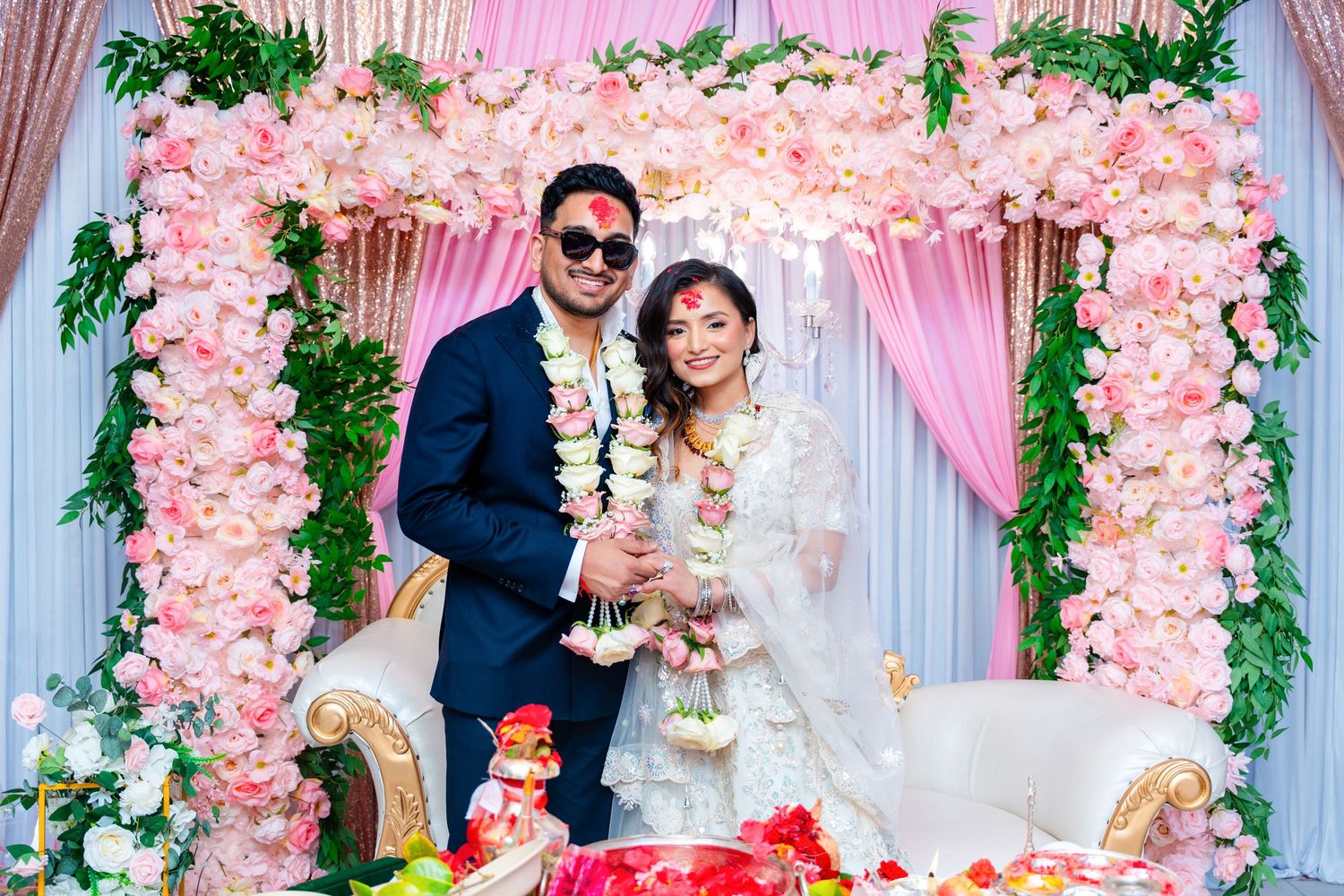 Elegant wedding celebration under pink floral arch with champagne toast.