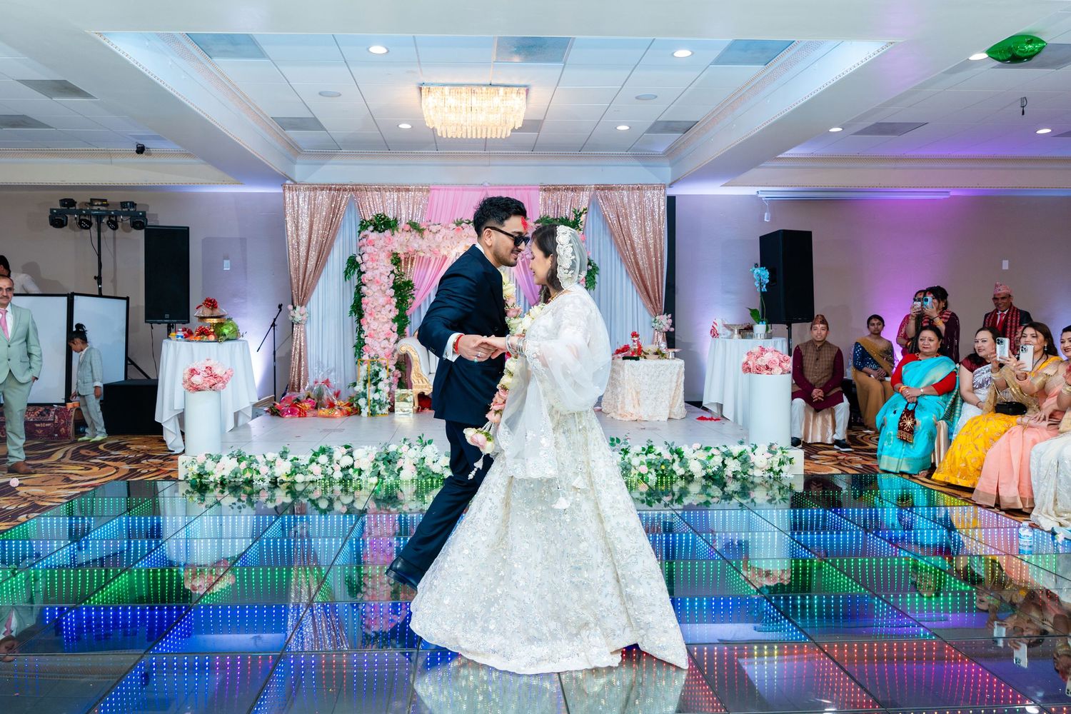 Couple performs first dance on illuminated LED floor at modern wedding reception.