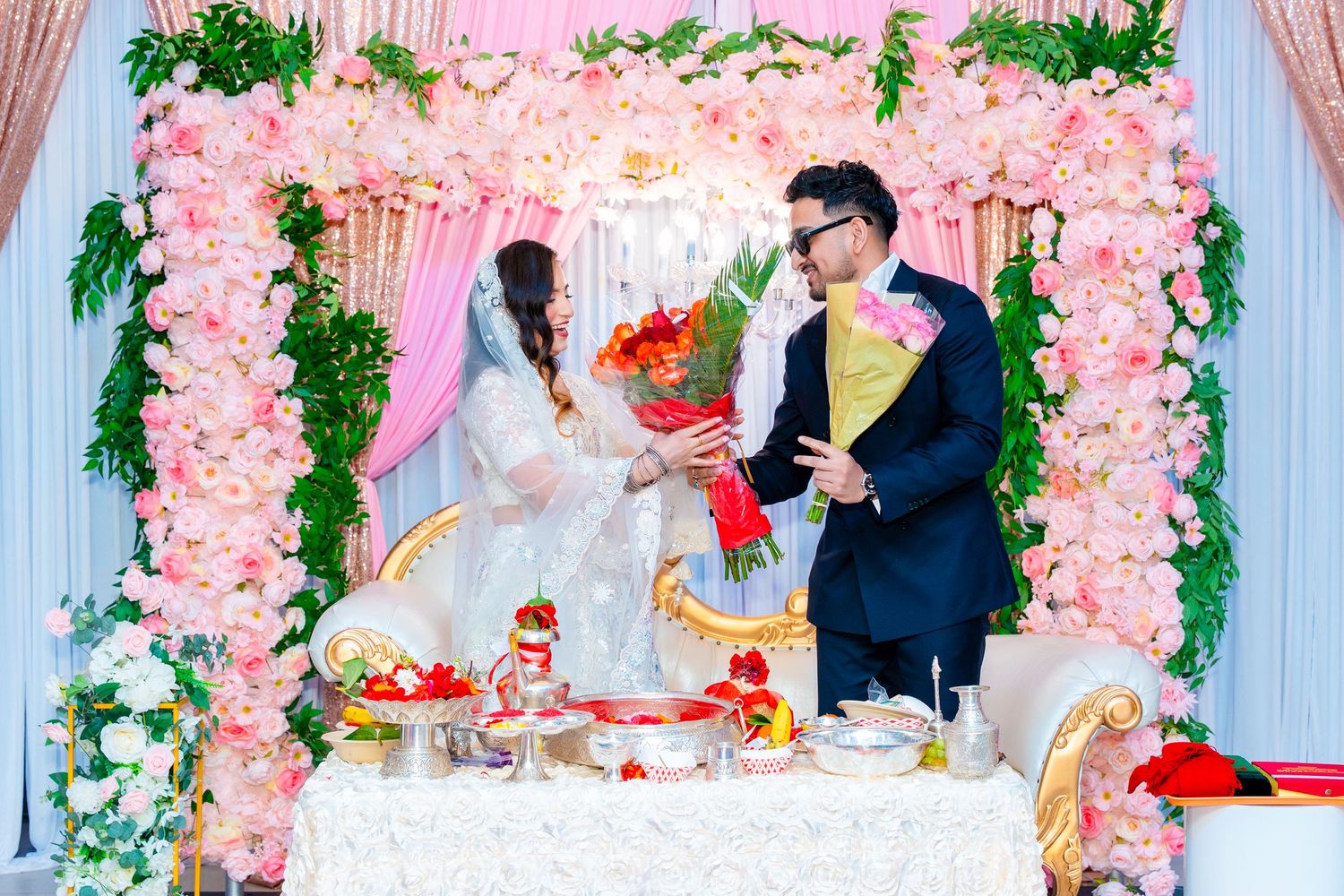 Wedding setup with pink floral arch and white decor for an intimate celebration.