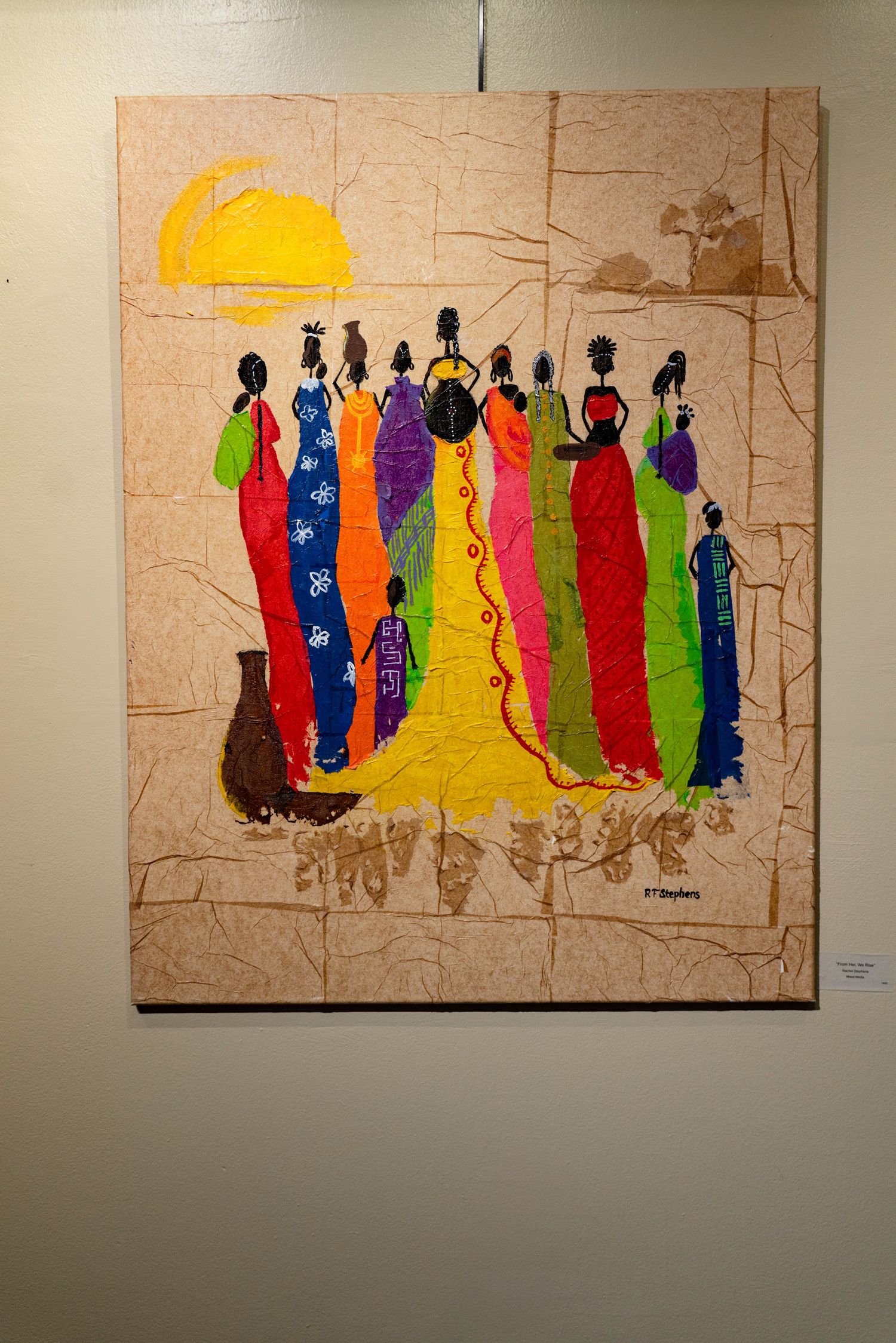 Colorful painting depicting silhouettes of figures in vibrant traditional dress against desert backdrop.