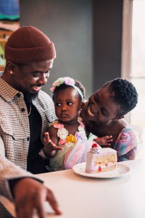 A loving family moment enjoying cake together at a table near a window.