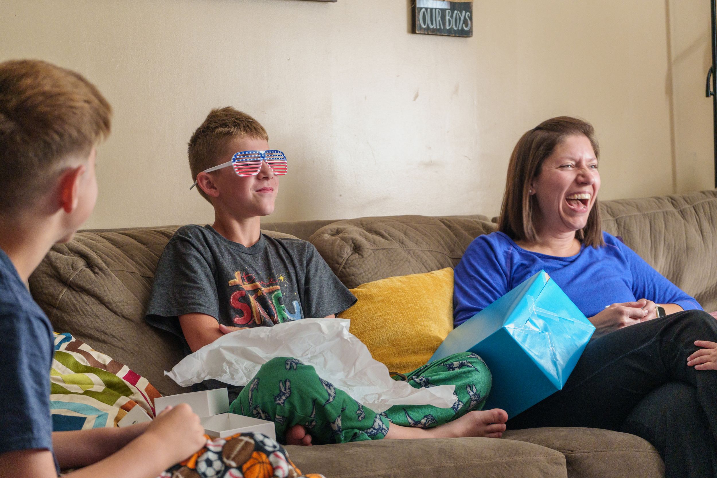 A group plays video games together on a couch while wearing 3D glasses and showing excited reactions.