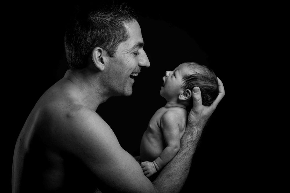 Un portrait réconfortant en noir et blanc montrant une interaction tendre entre un parent et un bébé.