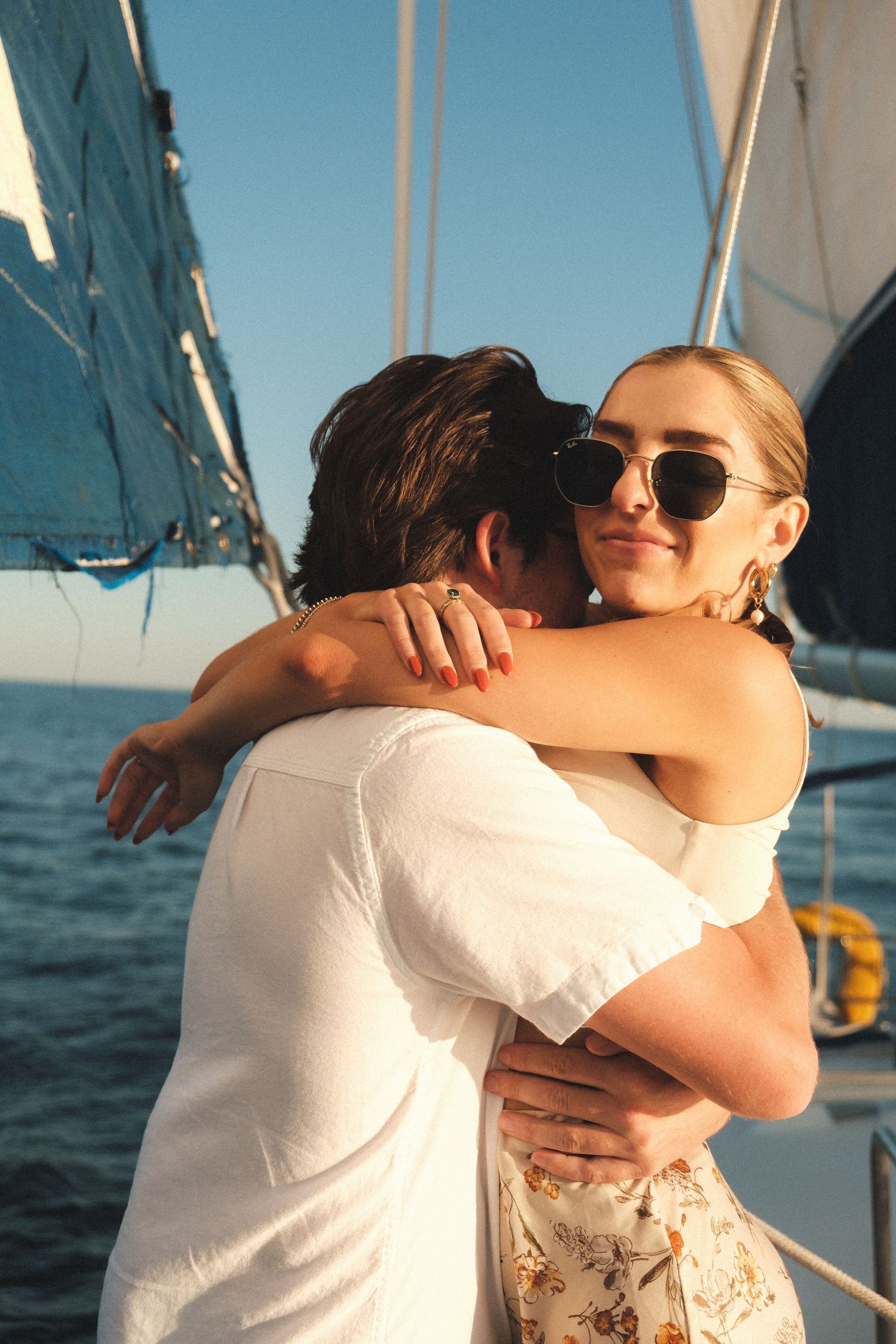 Romantic embrace on a sailboat with ocean and blue skies in the background.