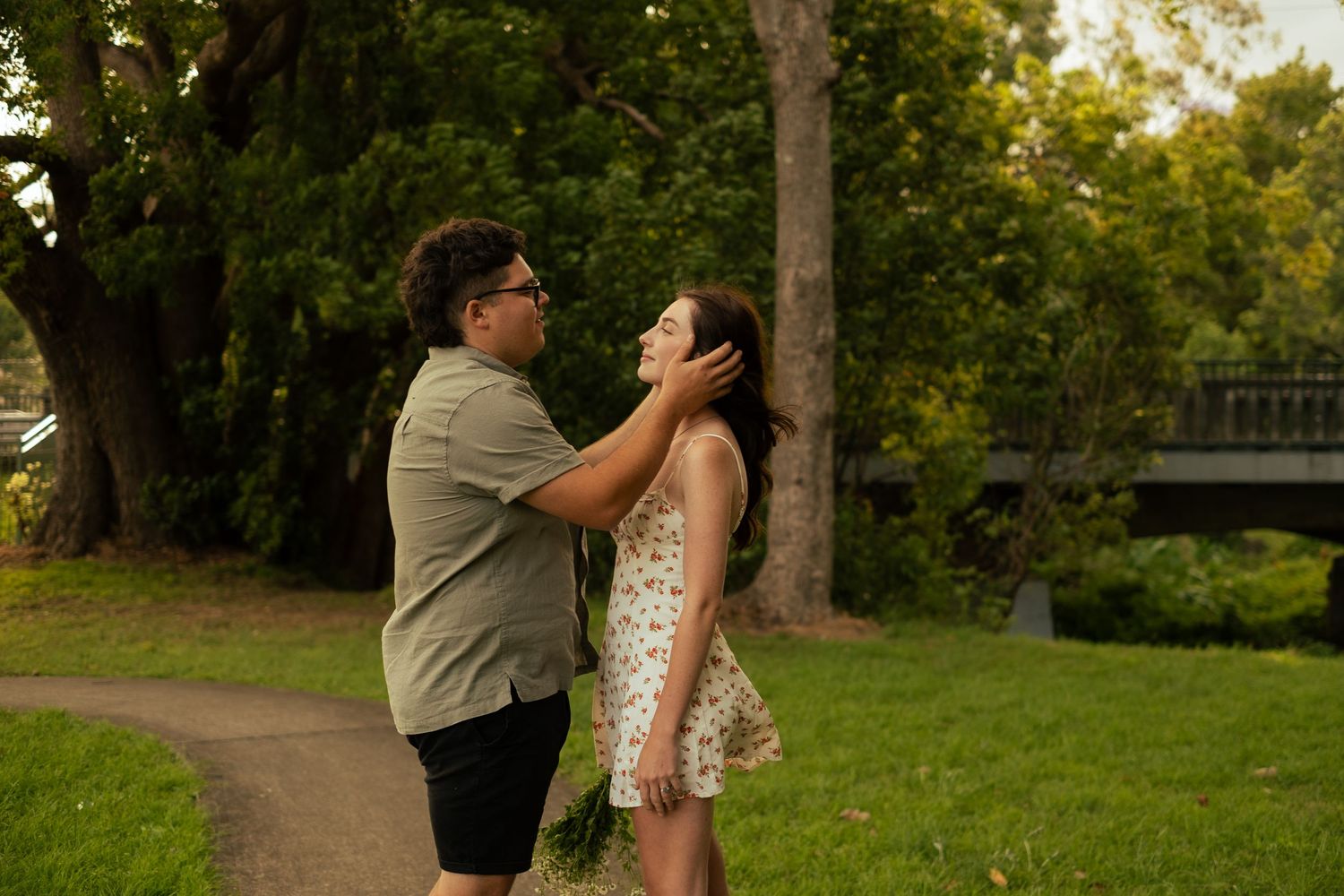 Romantic sunset moment between couple in a green park setting.