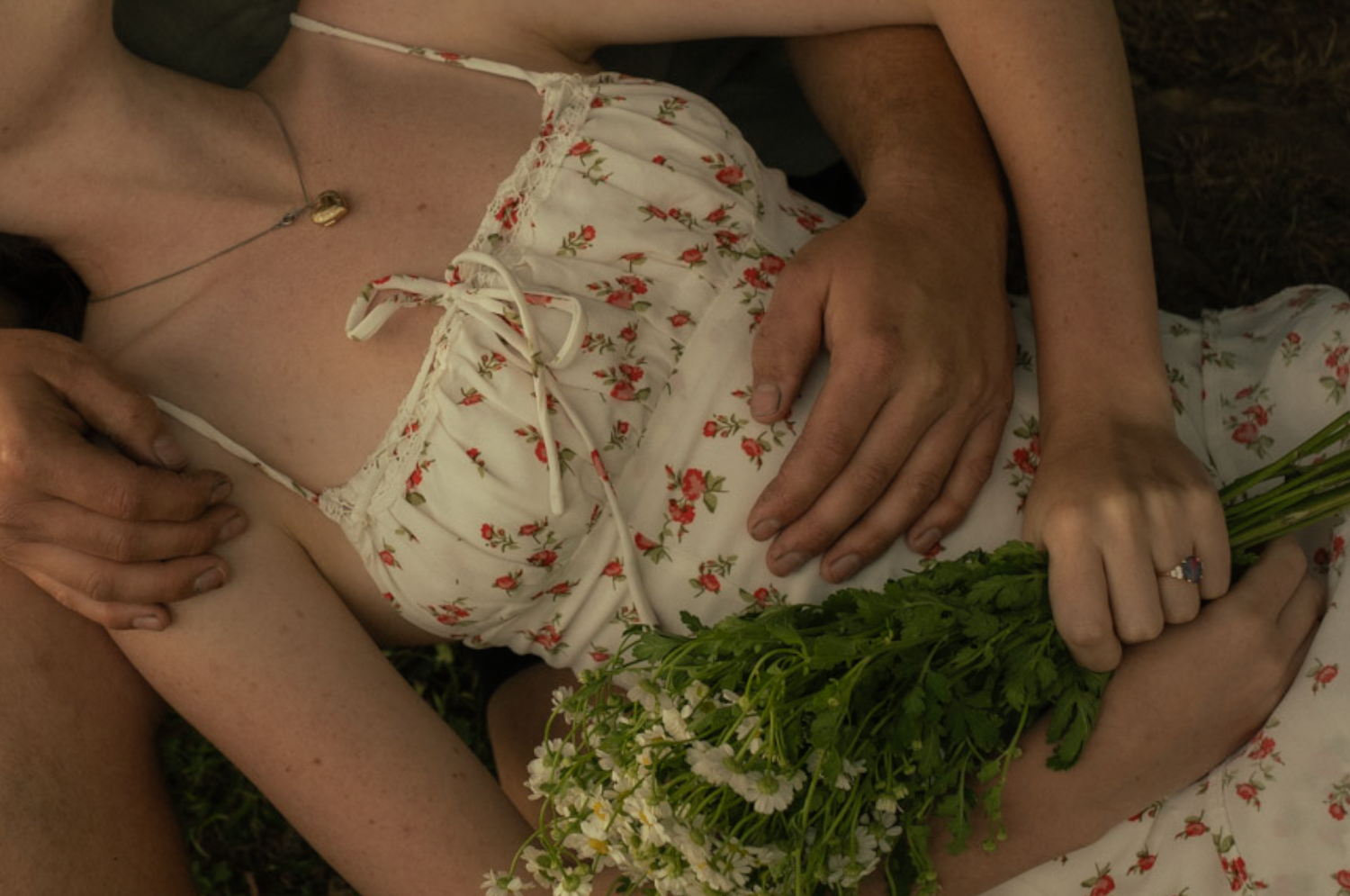 Person in floral dress holding fresh flowers in lap.