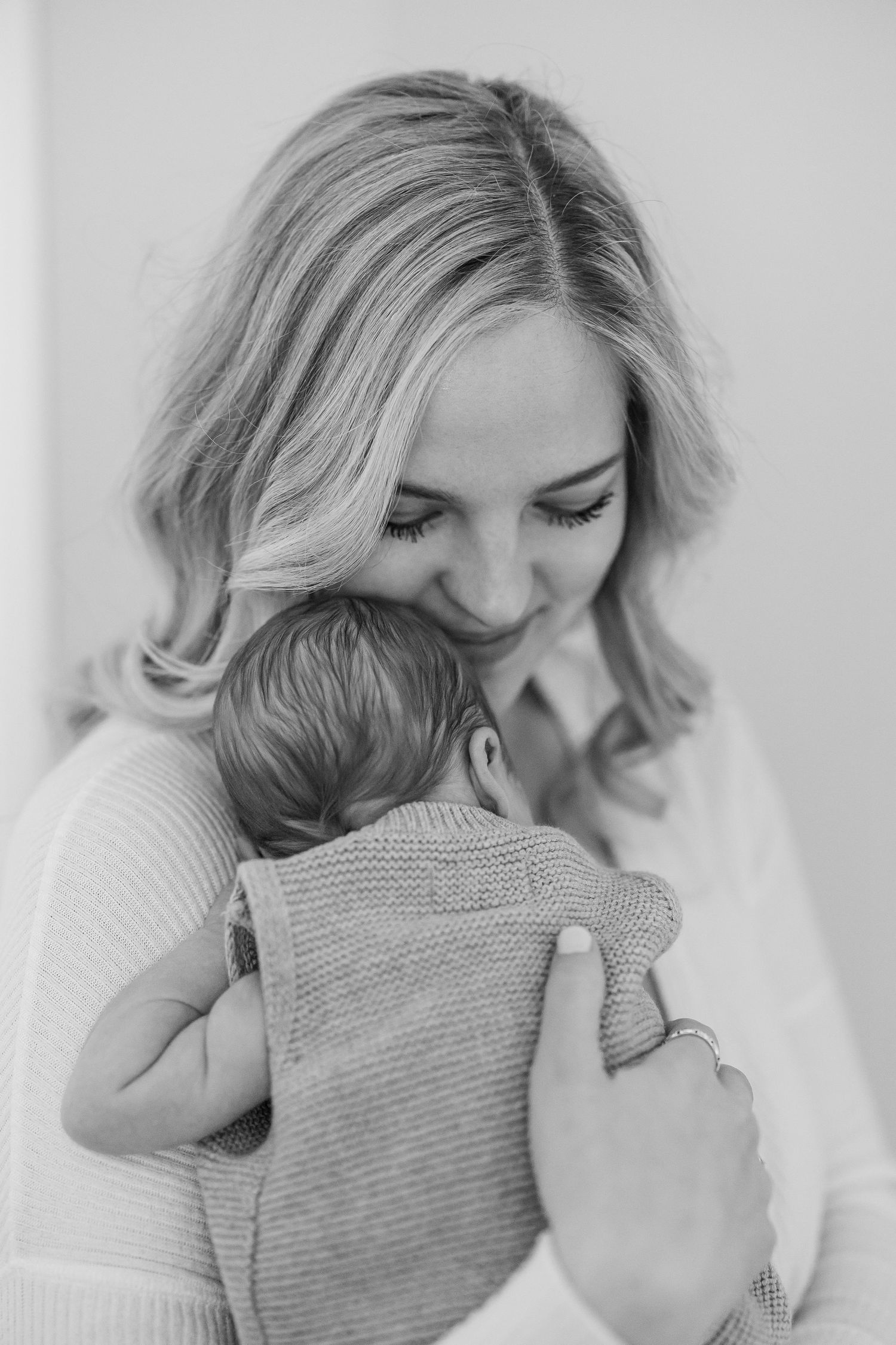 Intimate black and white portrait of tender moment with baby in gray sweater.
