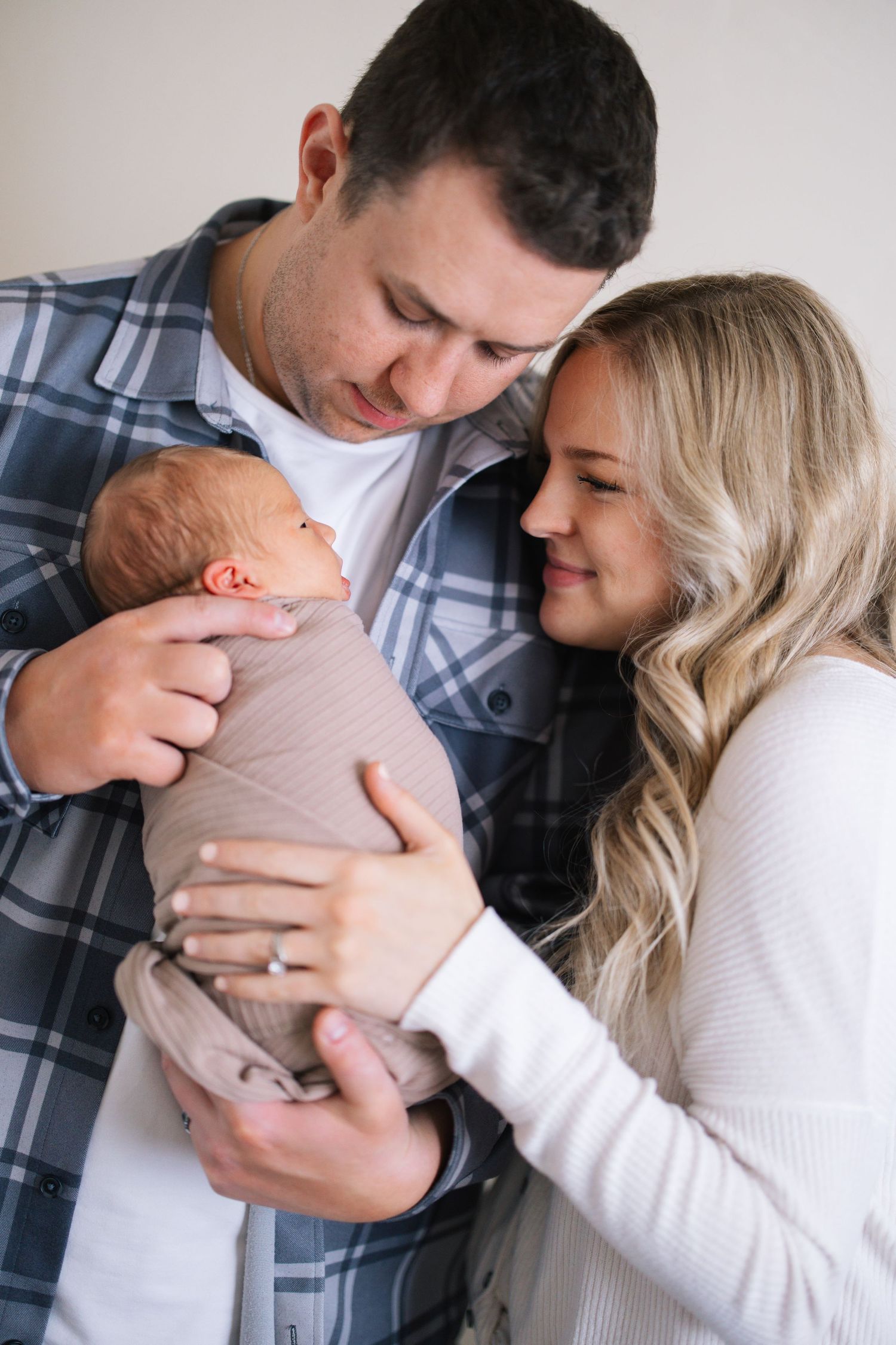 Intimate family moment with parents gazing at their swaddled newborn.