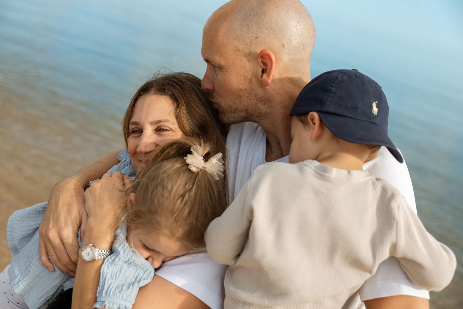 Family embracing together at the beach during golden hour.