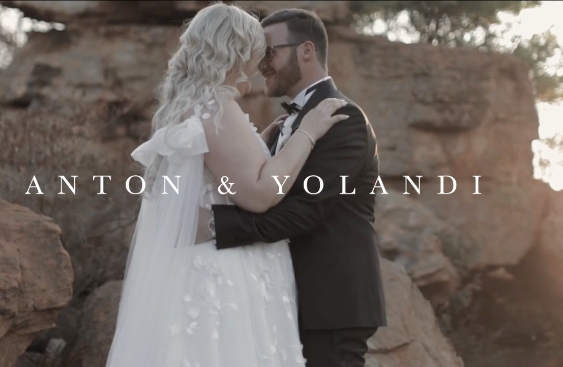 Romantic wedding portrait against desert rock formations at sunset.