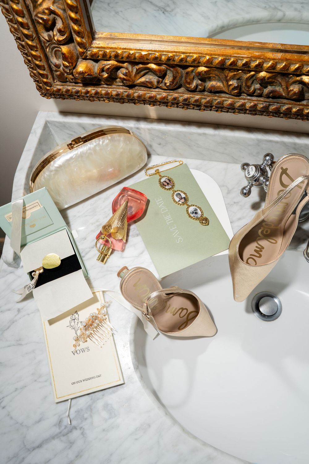 Elegant bridal flat lay on marble sink with Sam Edelman heels, pearl clutch, perfume, and vow booklets.