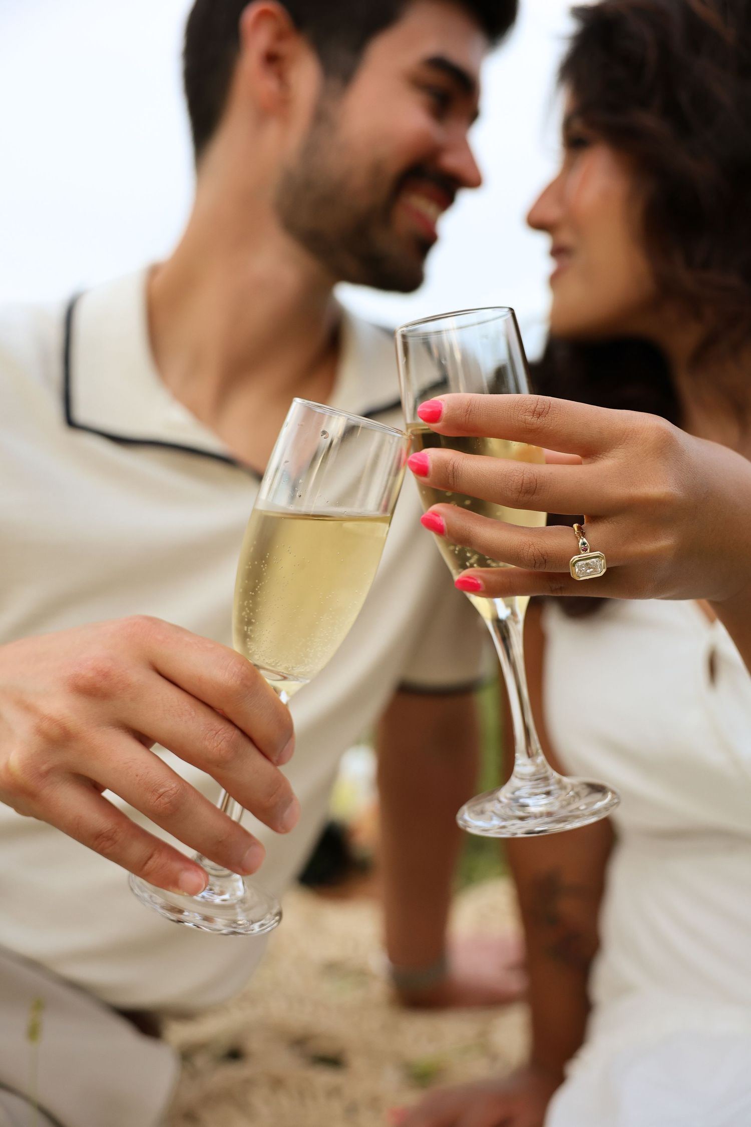 Multiple close-up shots of hands displaying an engagement ring against a light colored brick wall.