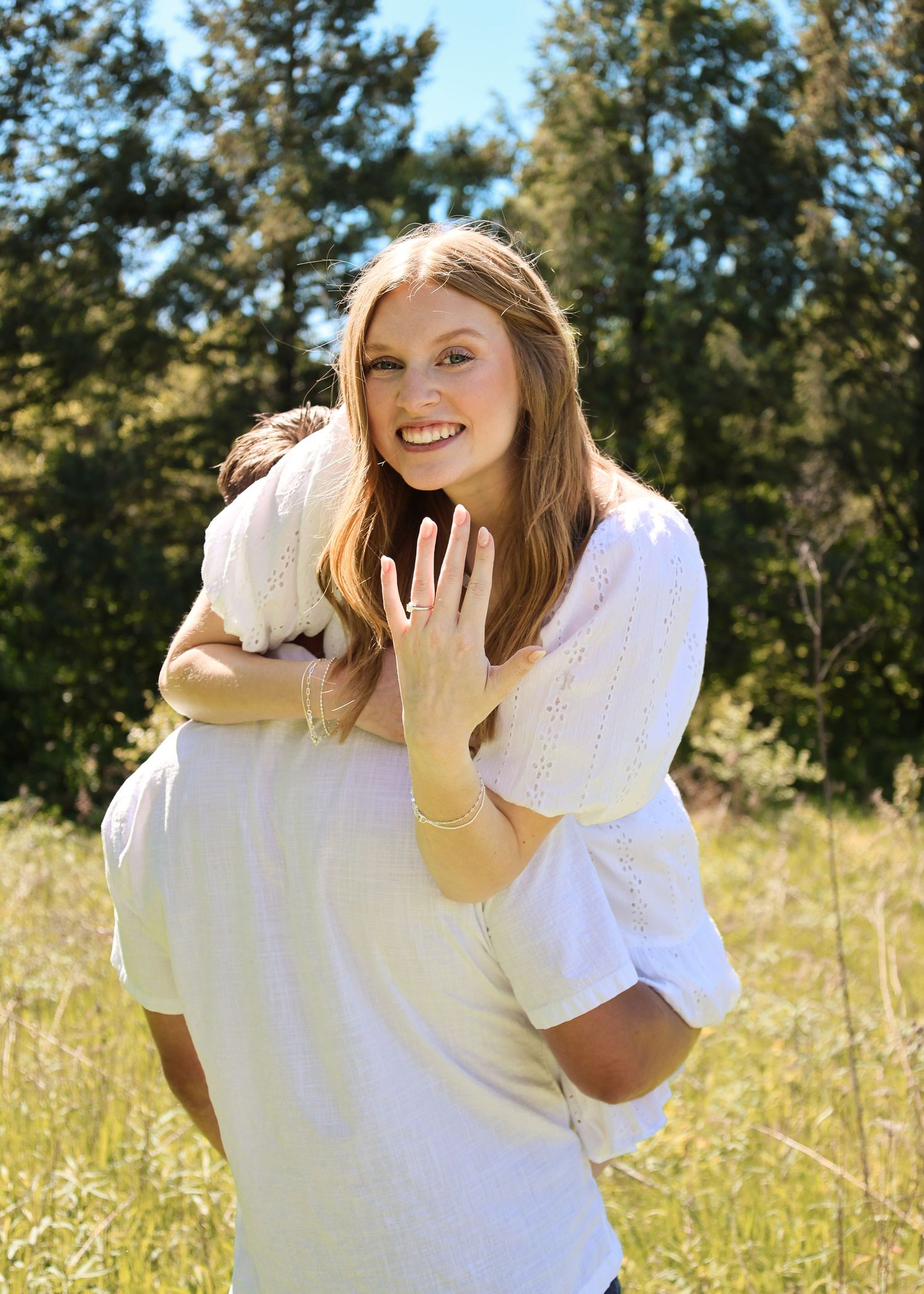 Multiple close-up shots of hands displaying an engagement ring against a light colored brick wall.