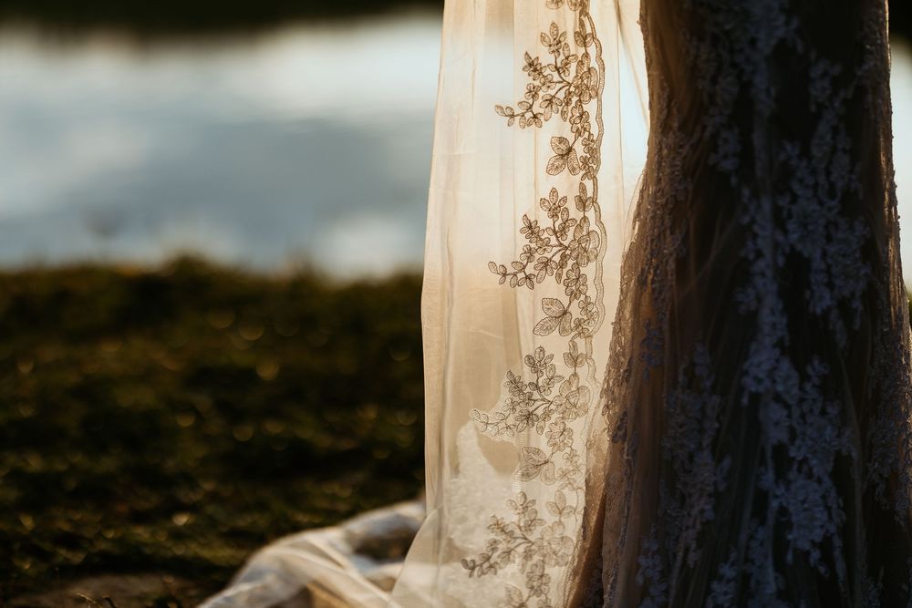 Close-up of intricate floral embroidery on a bridal gown train resting on mossy ground.