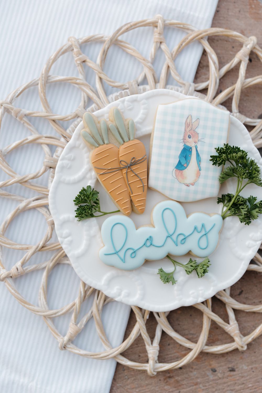 Peter Rabbit themed baby shower cookies with carrot and bunny designs on a white plate.
