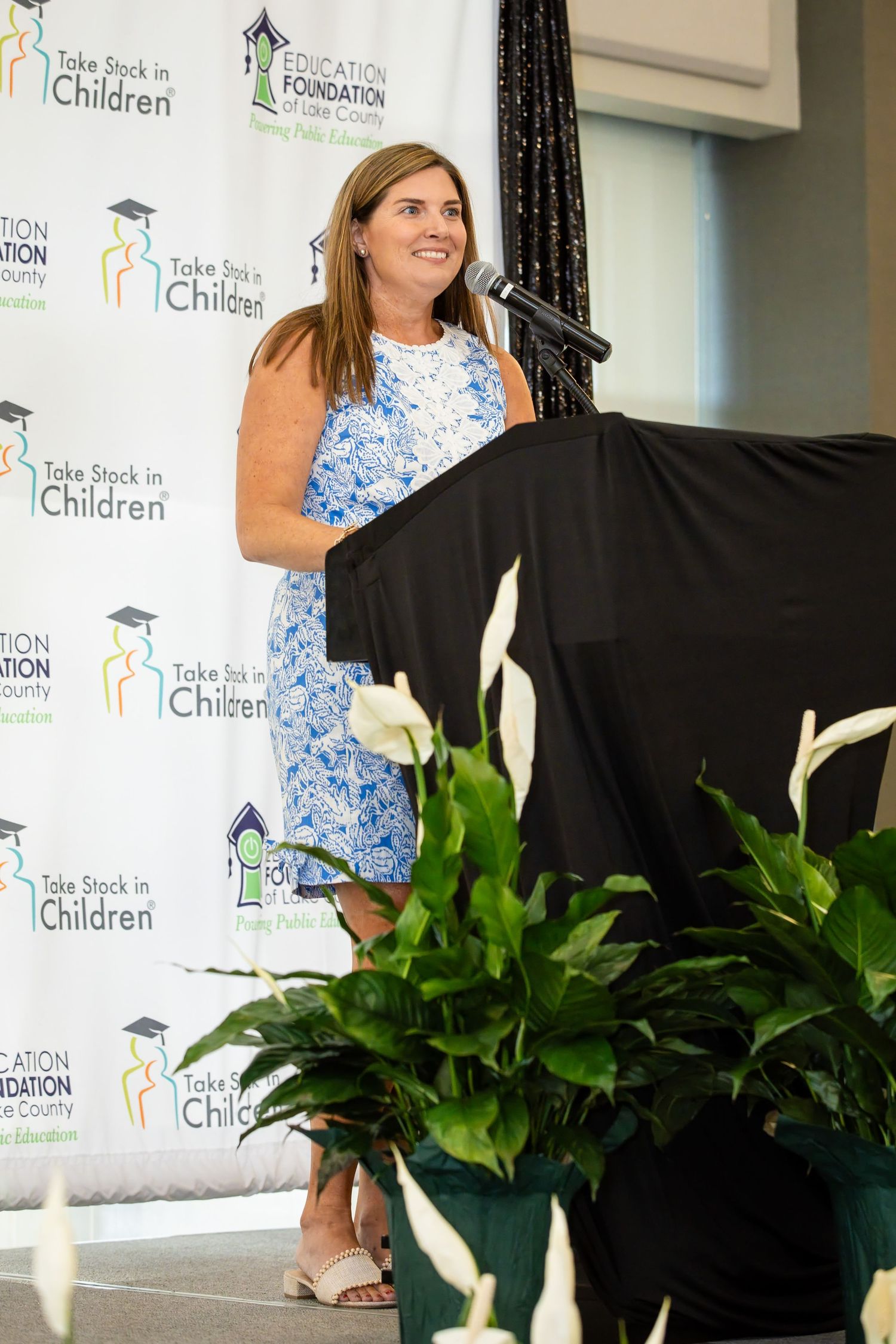 Two women pose together at a Take Stock in Children Education Foundation of Lake County event backdrop.