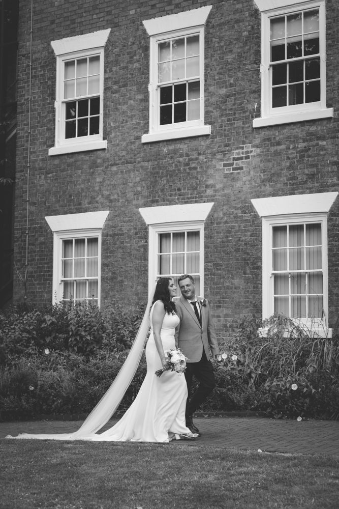 Black and white photo of a bride and groom walking hand in hand in front of west bridgford registry officein nottingha on their wedding day.