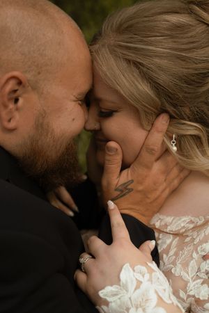 Groom tenderly cups brides face as they share an intimate forehead-to-forehead moment.