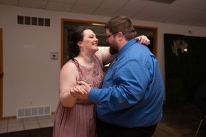 Couple shares a slow dance together at an indoor wedding reception celebration.