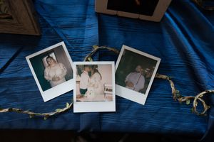 Three Polaroid wedding photos arranged on blue satin fabric with ribbon decoration.