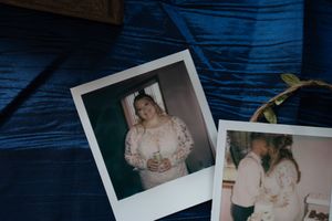 Two vintage Polaroid wedding photos displayed on blue velvet fabric with plant decoration.