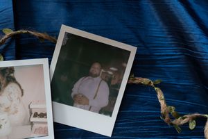 Two Polaroid photos on blue fabric with a decorative vine, featuring wedding party candid moments.