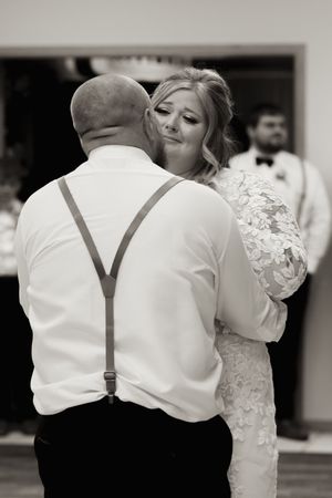 Black and white photo of bride and groom sharing emotional first dance at wedding reception.