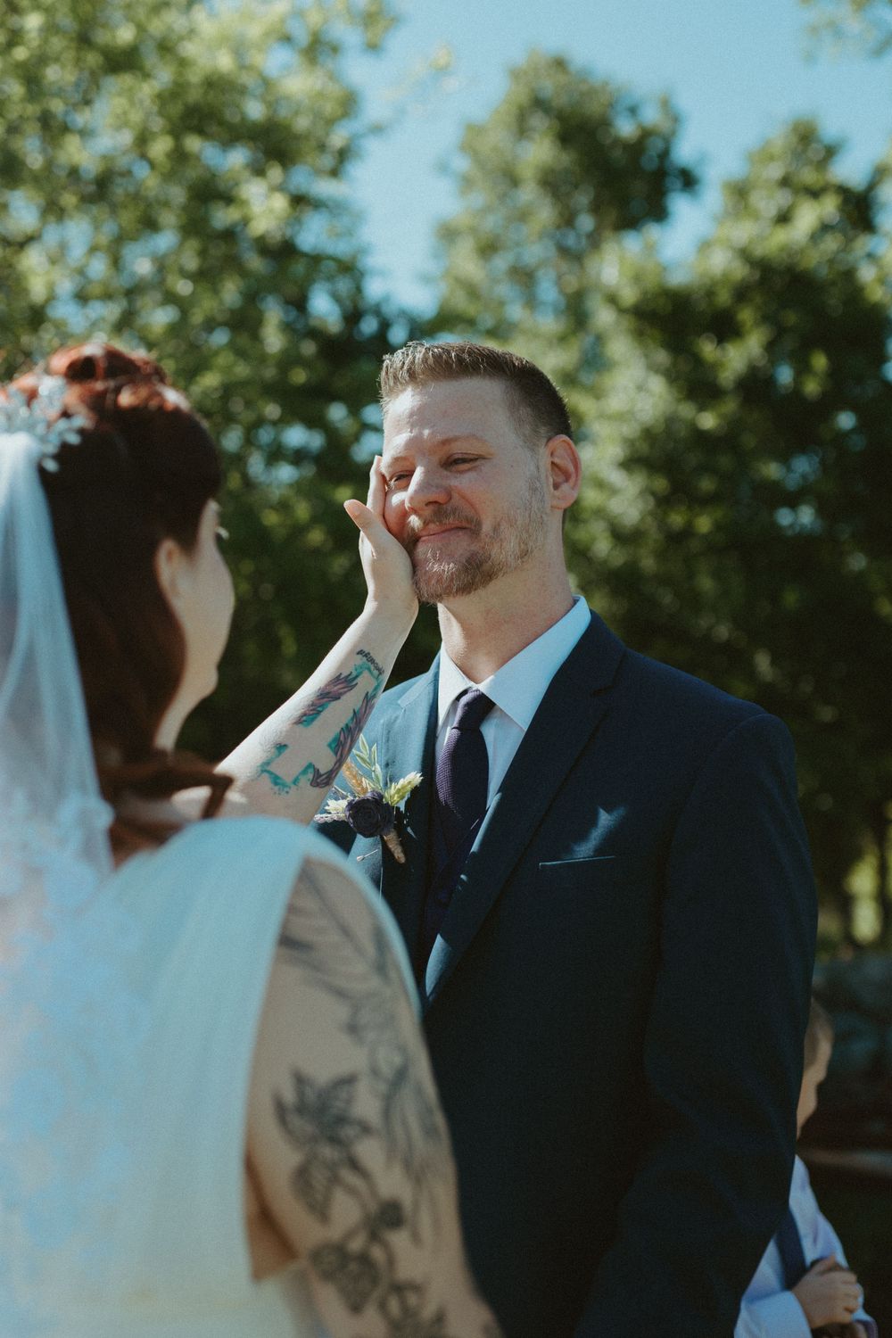 Bride gently touching the groom's cheek during an emotional outdoor wedding ceremony in Wimberley, TX.