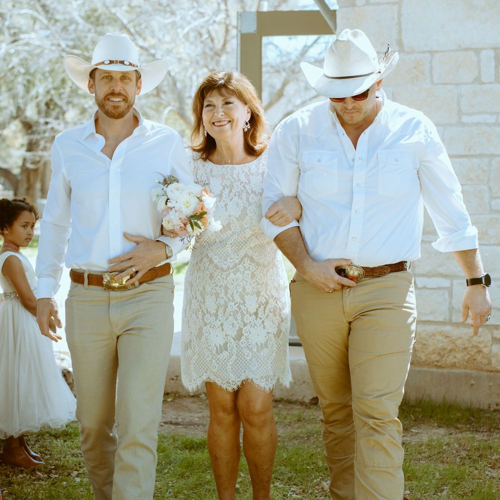 Candid wedding processional photography at a Wimberley, Texas venue, featuring a western-style wedding party walking outdoors.