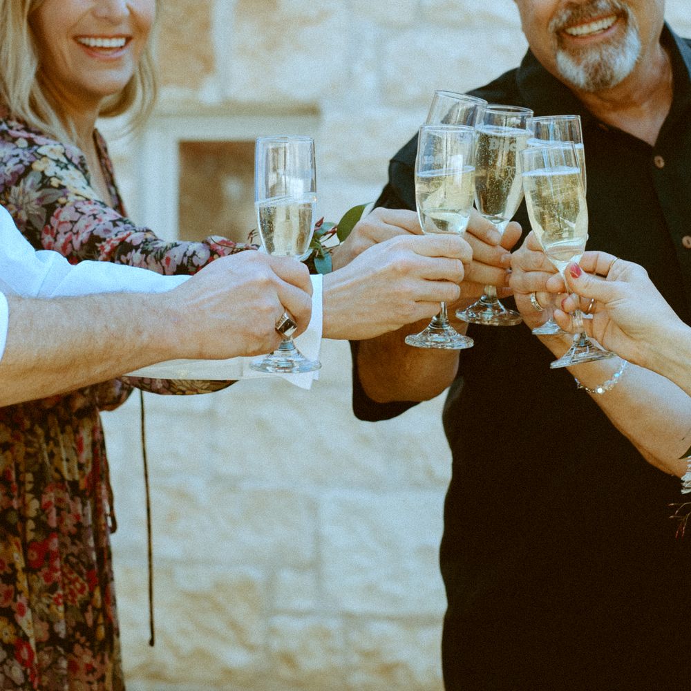 Candid photography of family and friends celebrating with a champagne toast at an outdoor reception in Wimberley, Texas.