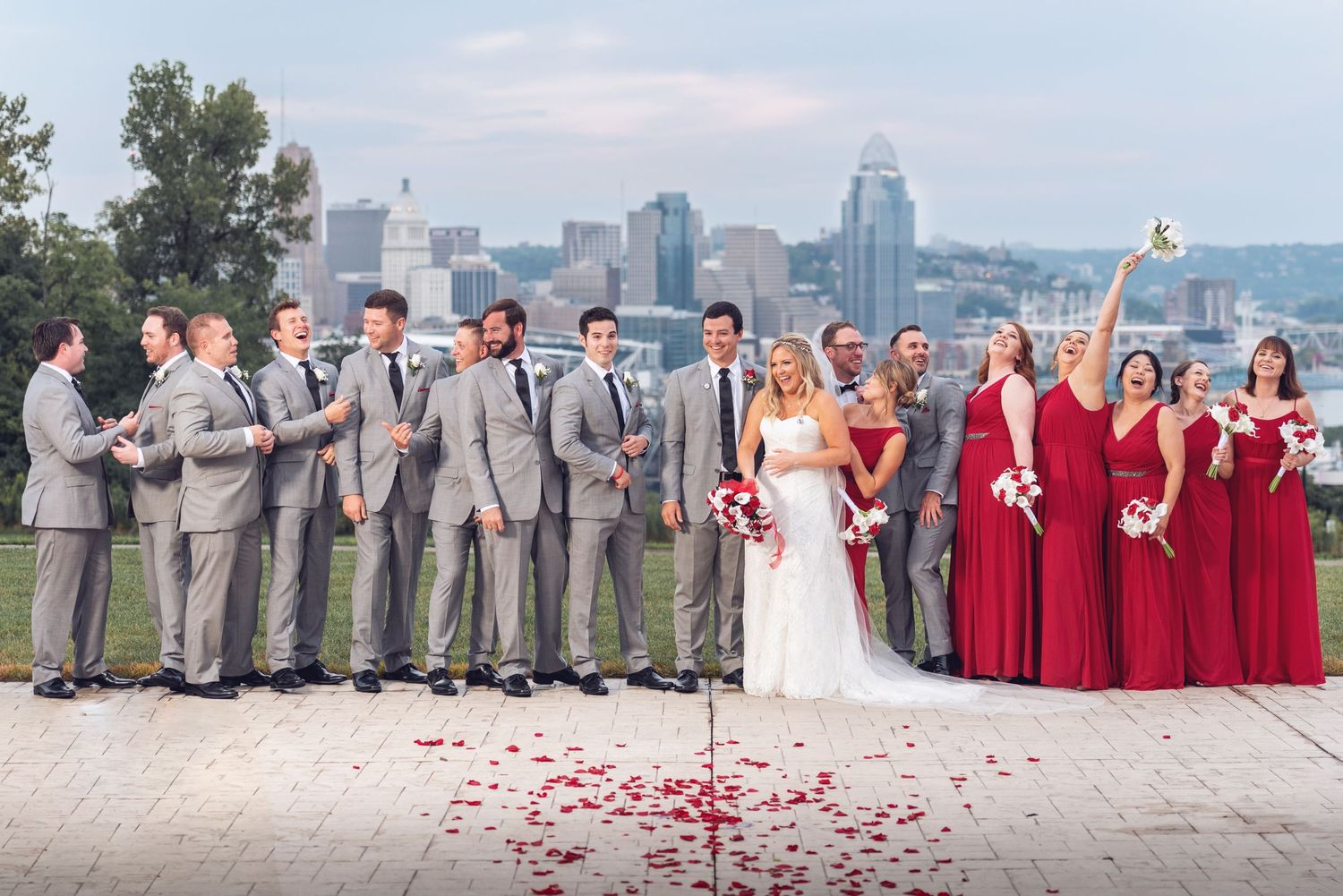 Wedding party members lined up against urban skyline backdrop wearing coordinated formal attire.