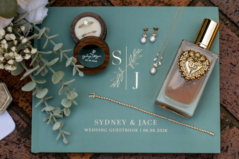 Wedding guestbook for Sydney and Jace dated 06.06.2026 with perfume, earrings, ring box, and bracelet.