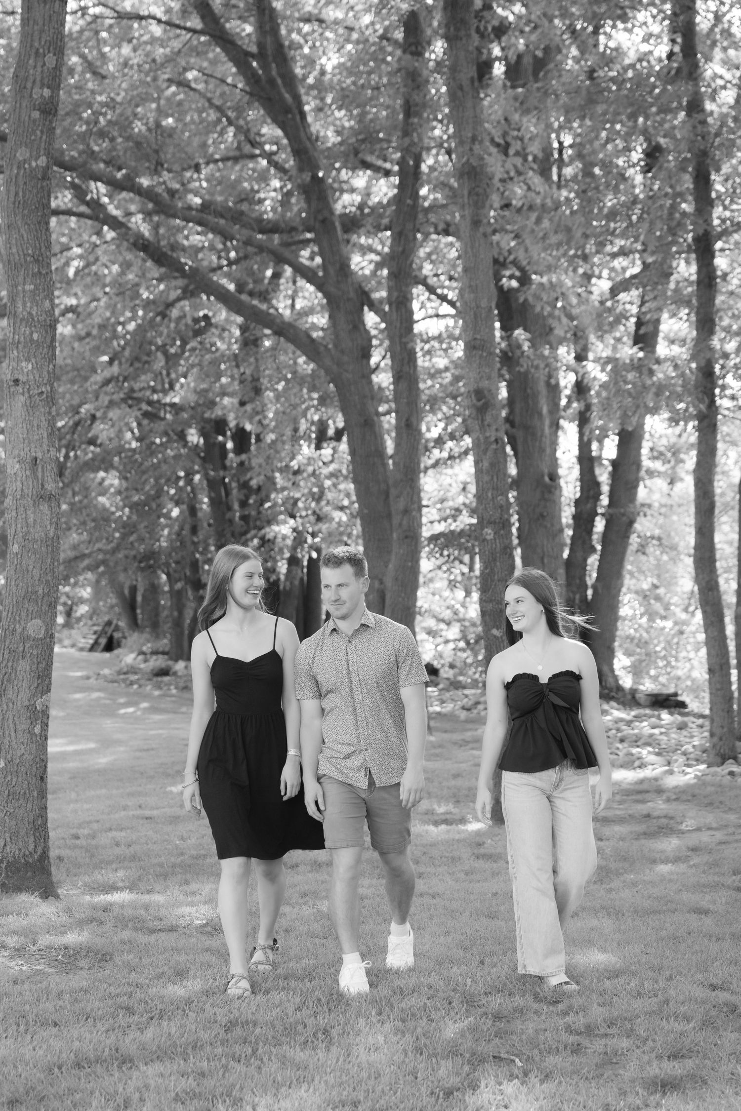 three teenage siblings walking together for candid summer family portraits at the cabin on lake wissota in chippewa falls, wi