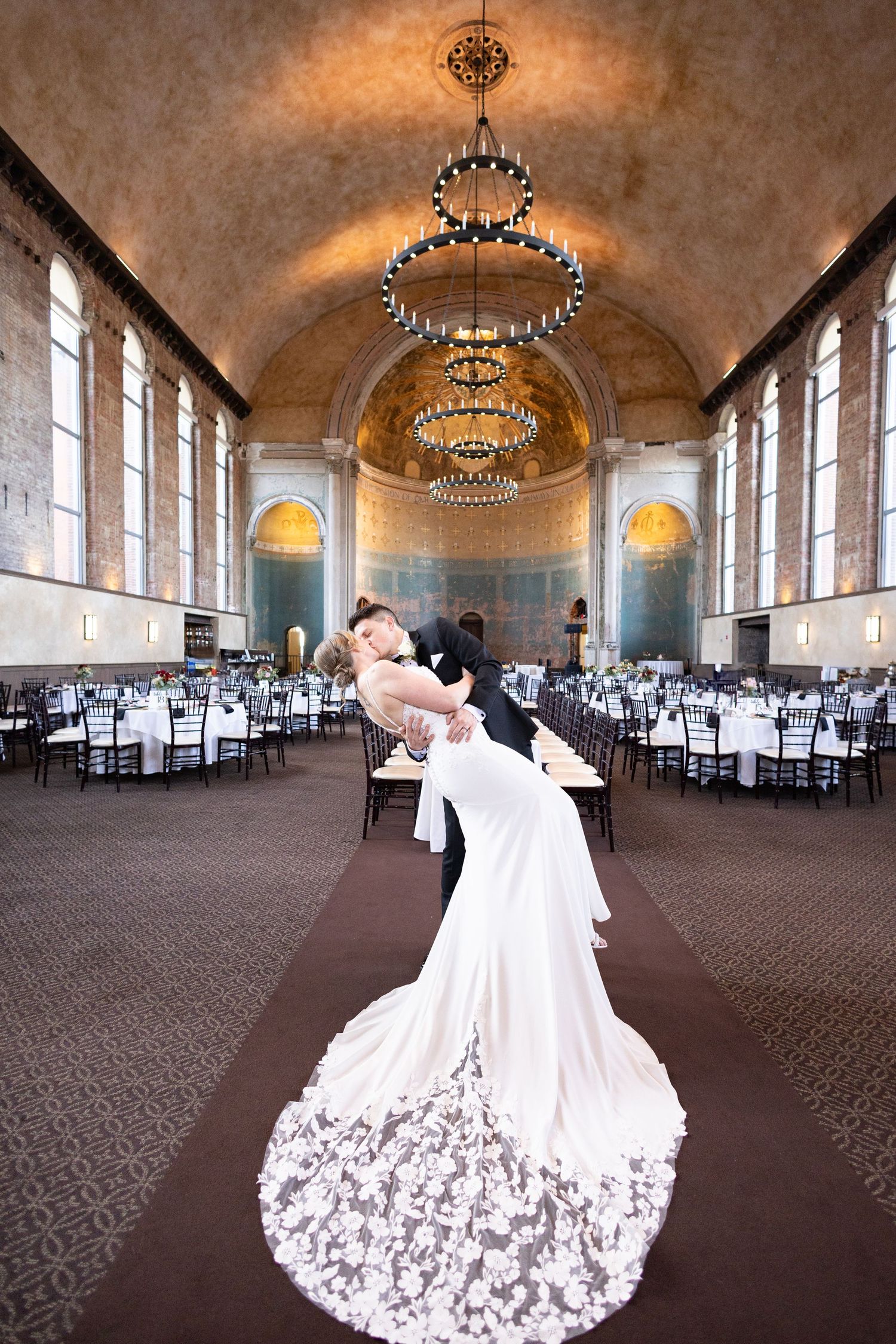 Bride and groom share first dance under elegant chandelier in grand ballroom at the historic Monastery Cincinnati wedding venue.