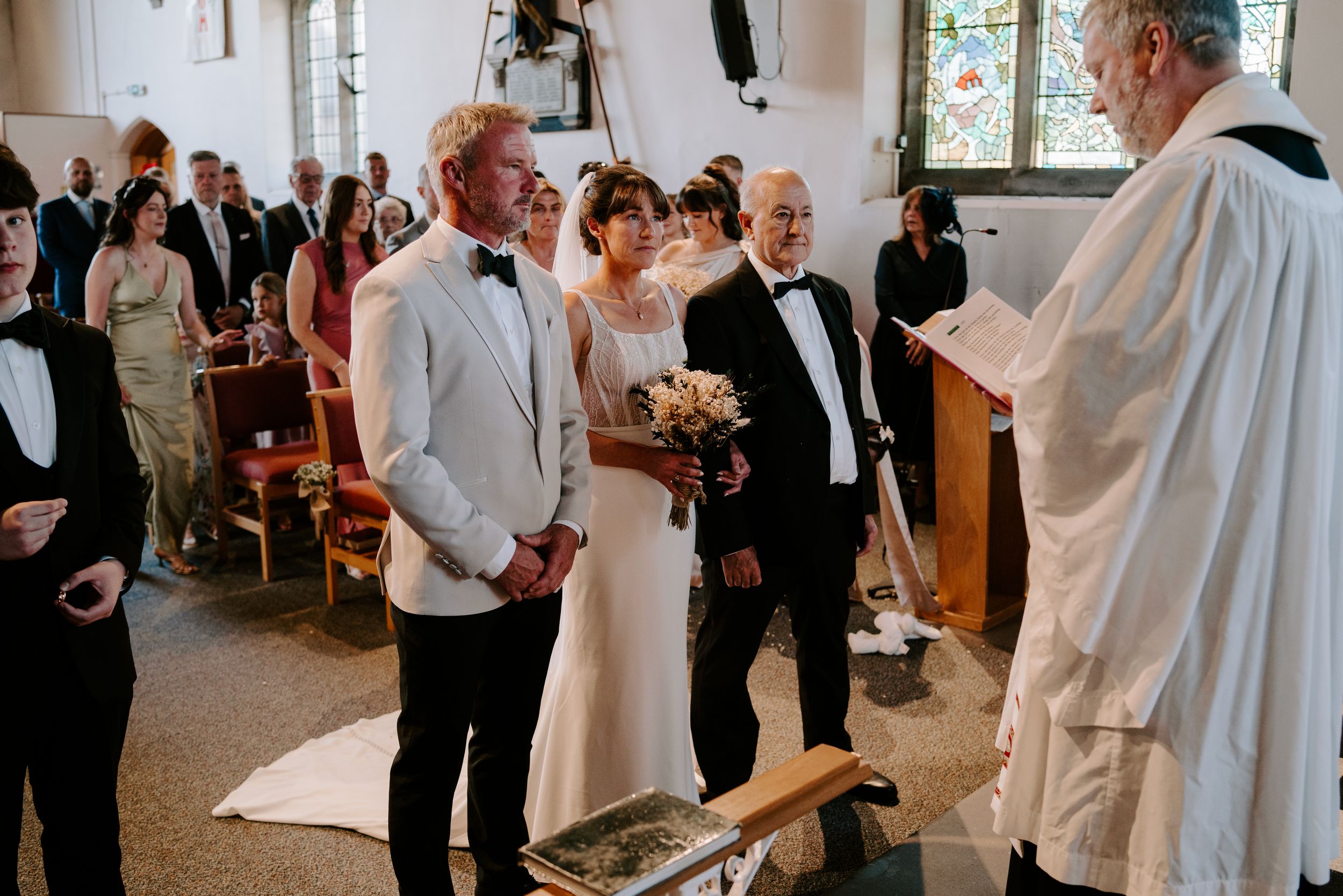Bride and groom stand before officiant during traditional church wedding ceremony.