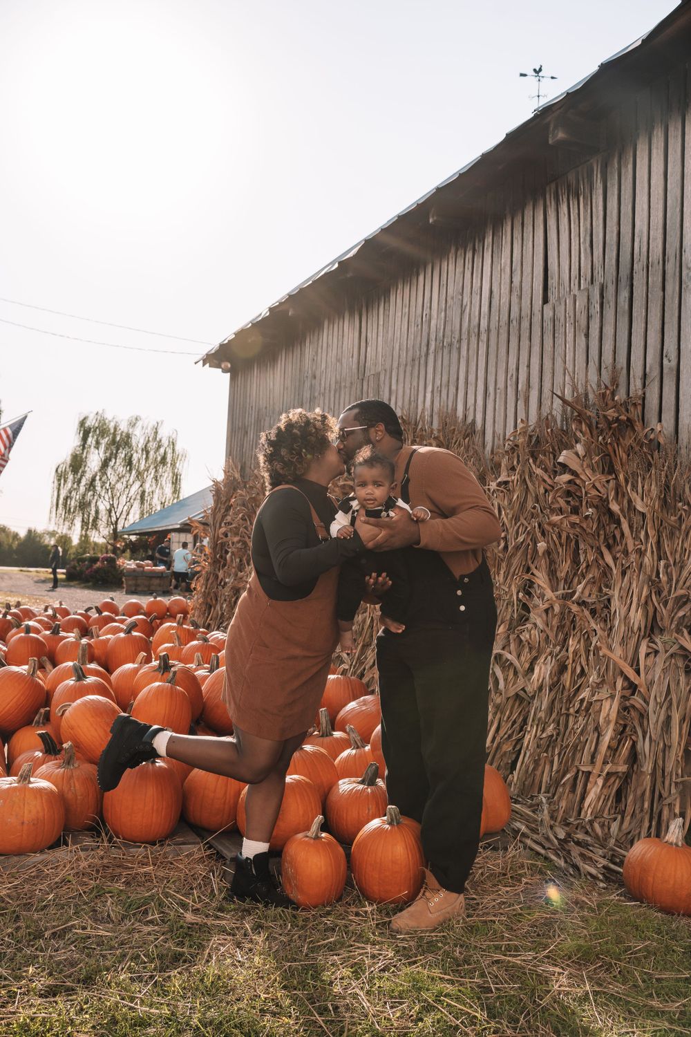 A loving autumn scene at a pumpkin patch with rustic barn backdrop.