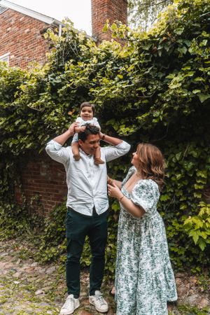 A family shares a joyful moment together against an ivy-covered brick wall.
