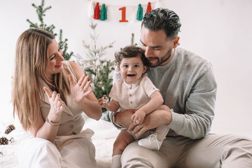 Family sitting together on white couch during holiday season with Christmas tree in background.