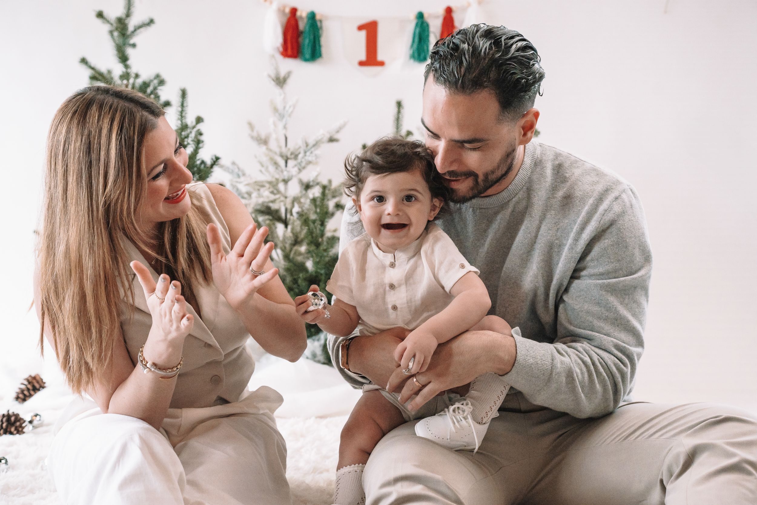 Family sitting together on white couch during holiday season with Christmas tree in background.