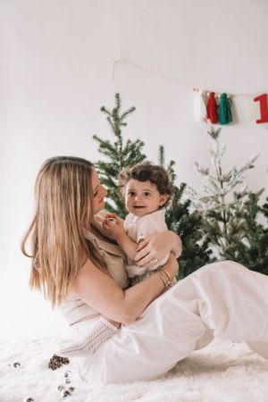 A cozy holiday scene with a Christmas tree and white bedding while sharing a tender moment on a winter morning.