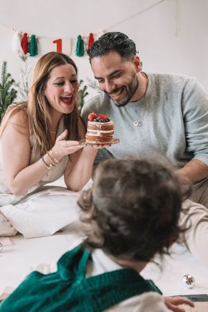 A family celebrates with a small cake decorated with berries during a first birthday photoshoot.