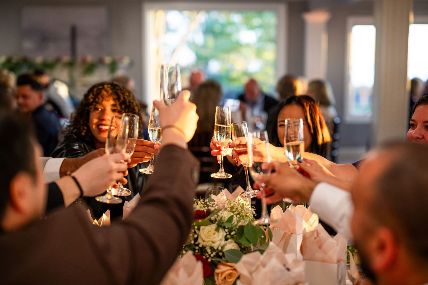 Wedding guests raising champagne glasses in a celebratory toast during reception.
