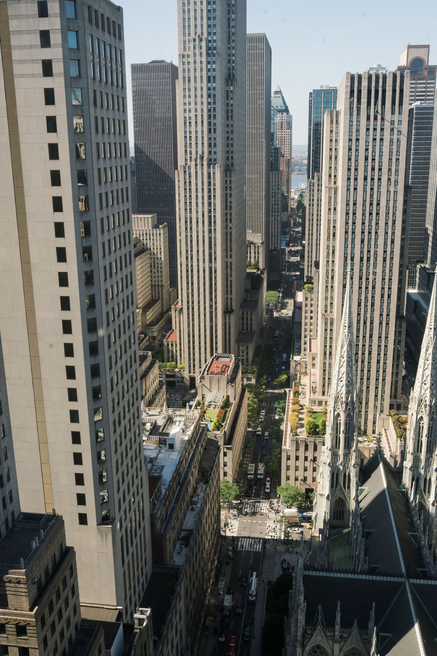 Aerial view of tall skyscrapers and buildings in New York City's urban landscape on a sunny day.